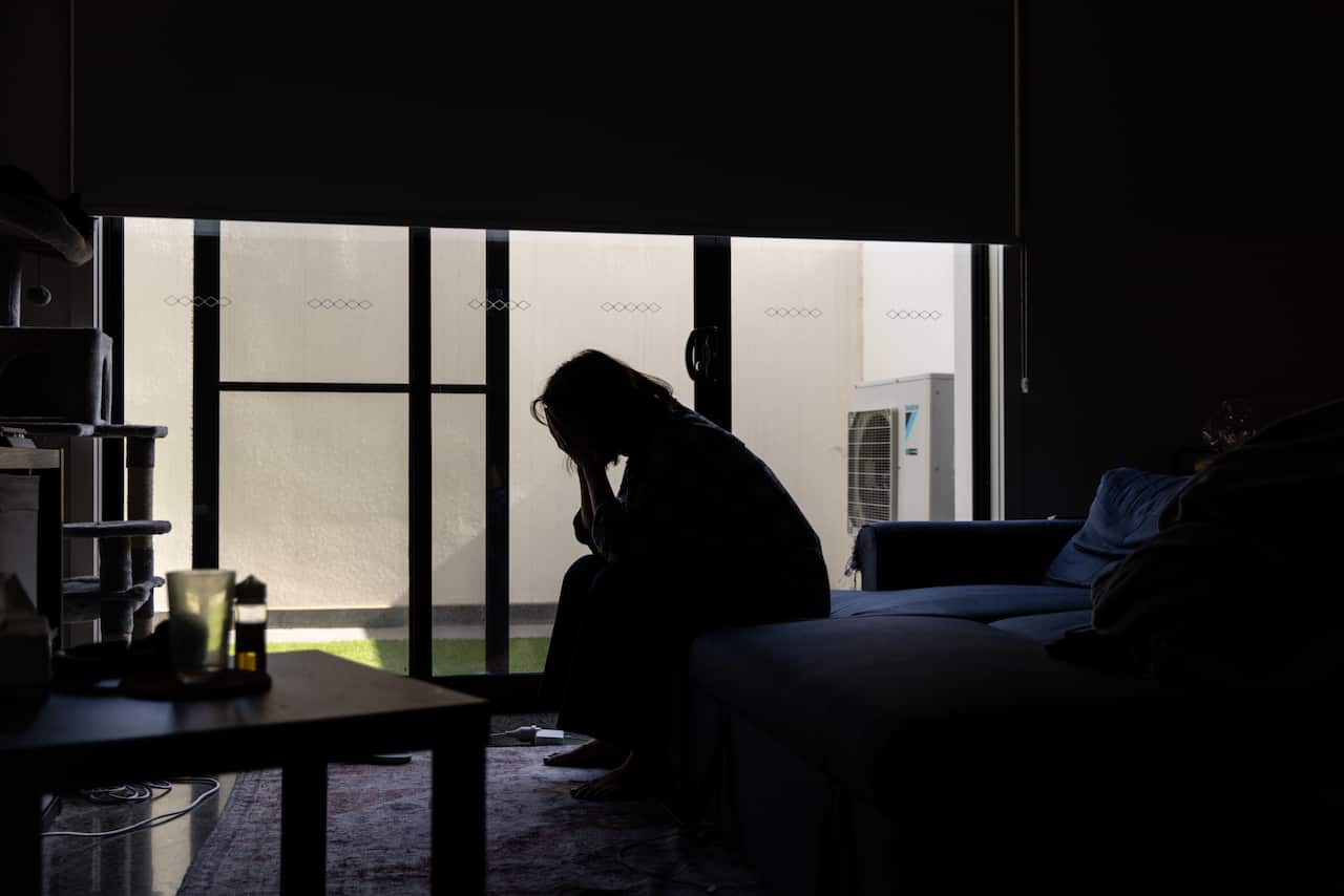 A woman sitting on a couch with her head in her hands