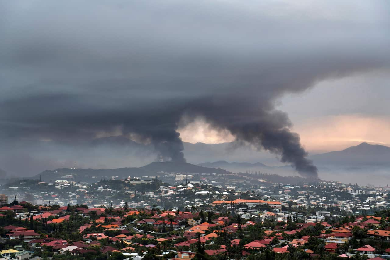 Smoke rises from various places in an overview of an area in Noumea.