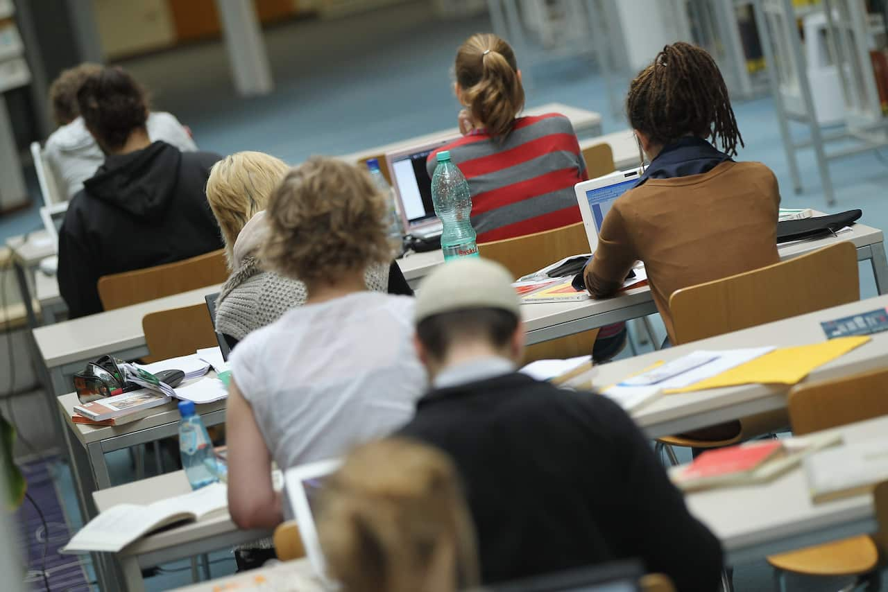 Young people sit at desks