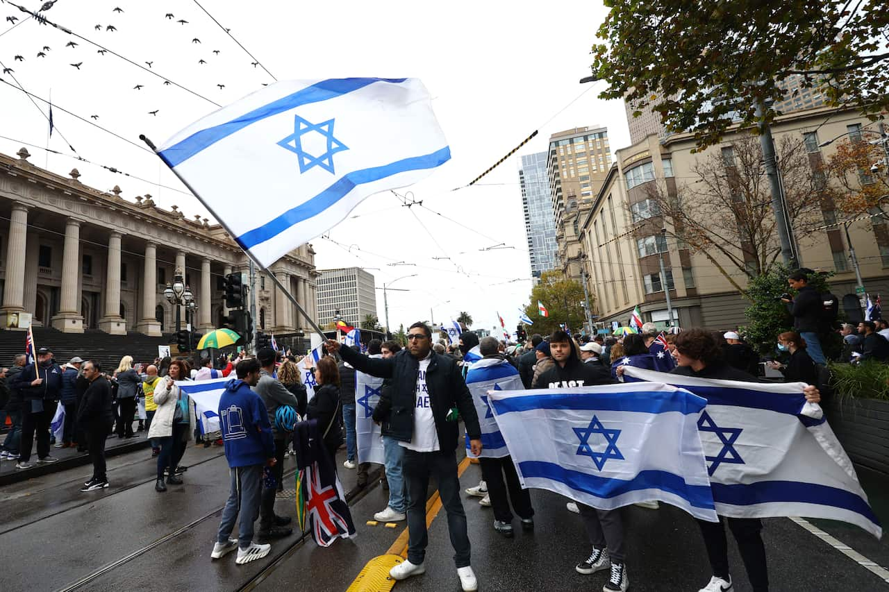 A group of people holding Israeli flags in the middle of a street.