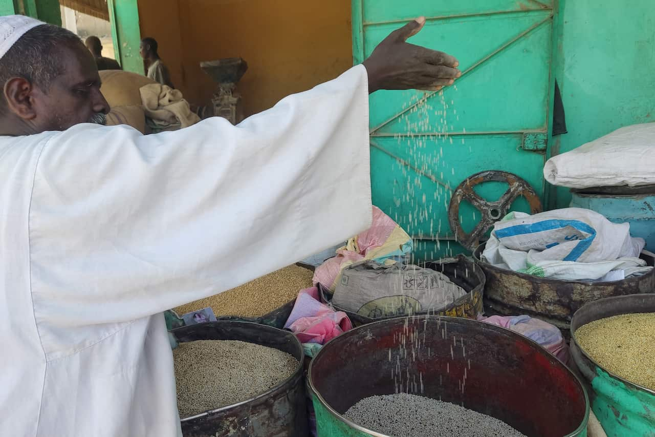 A man pours grain from between his fingers from a large barrel.