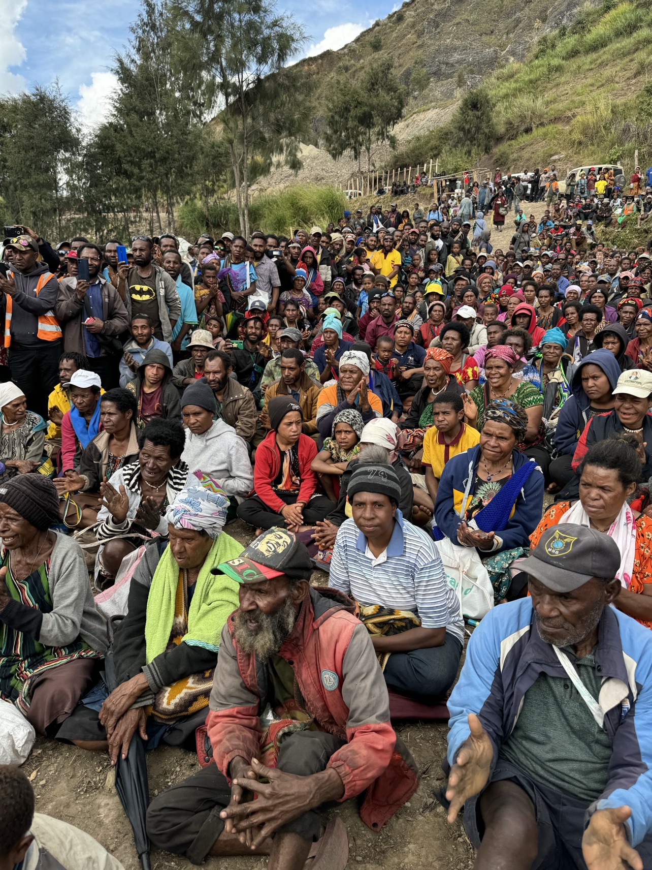 A crowd of people sit on the ground 