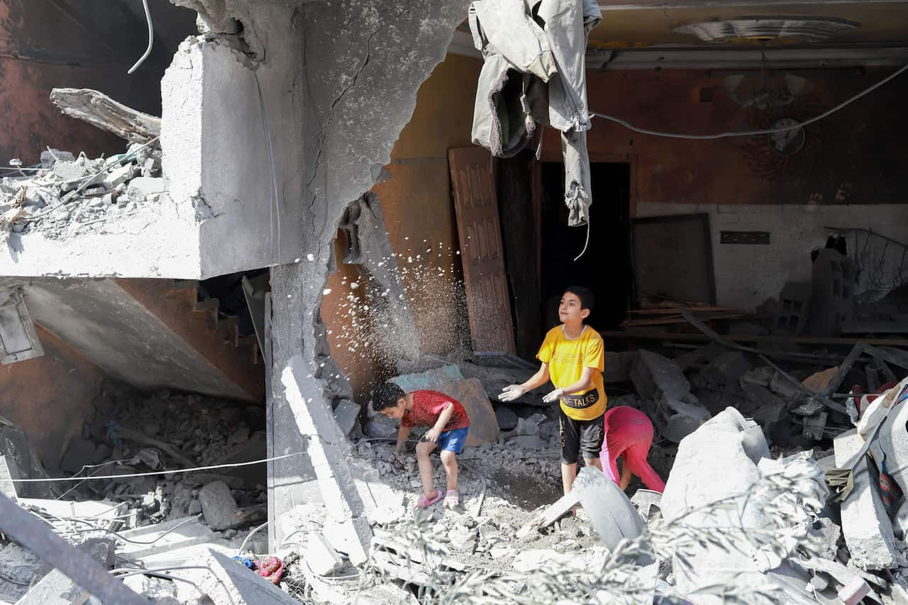 Palestinian children play on the balcony of their home amongst the rubble after the Israeli army withdrew from Nusairat in Gaza.