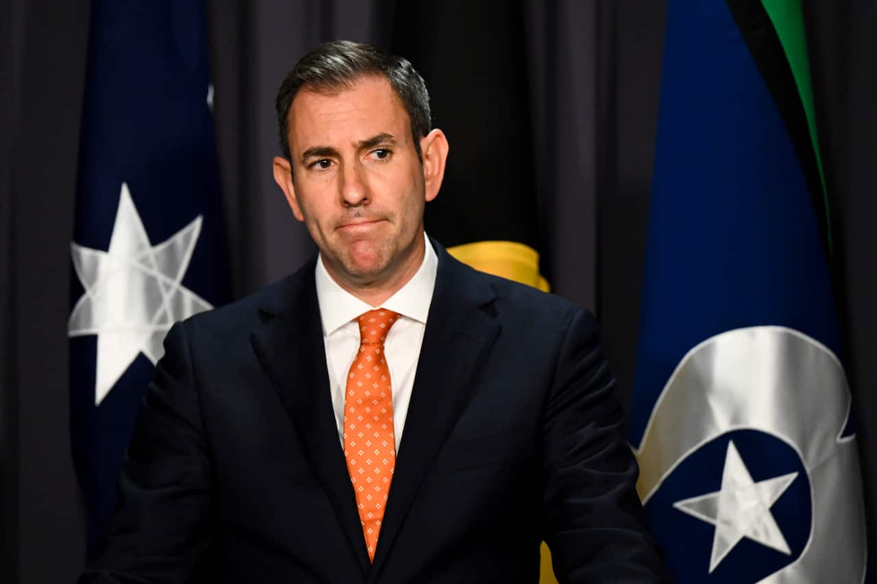 Jim Chalmers standing in front of Australian, Aboriginal and Torres Strait Islander flags.