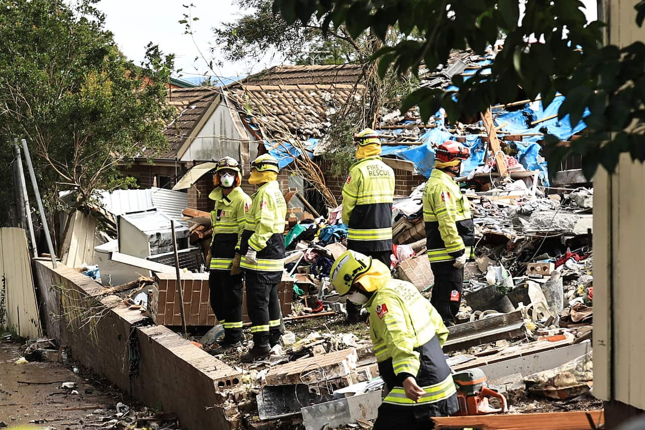 Fire and rescue personnel search though rubble following the explosion of a townhouse.