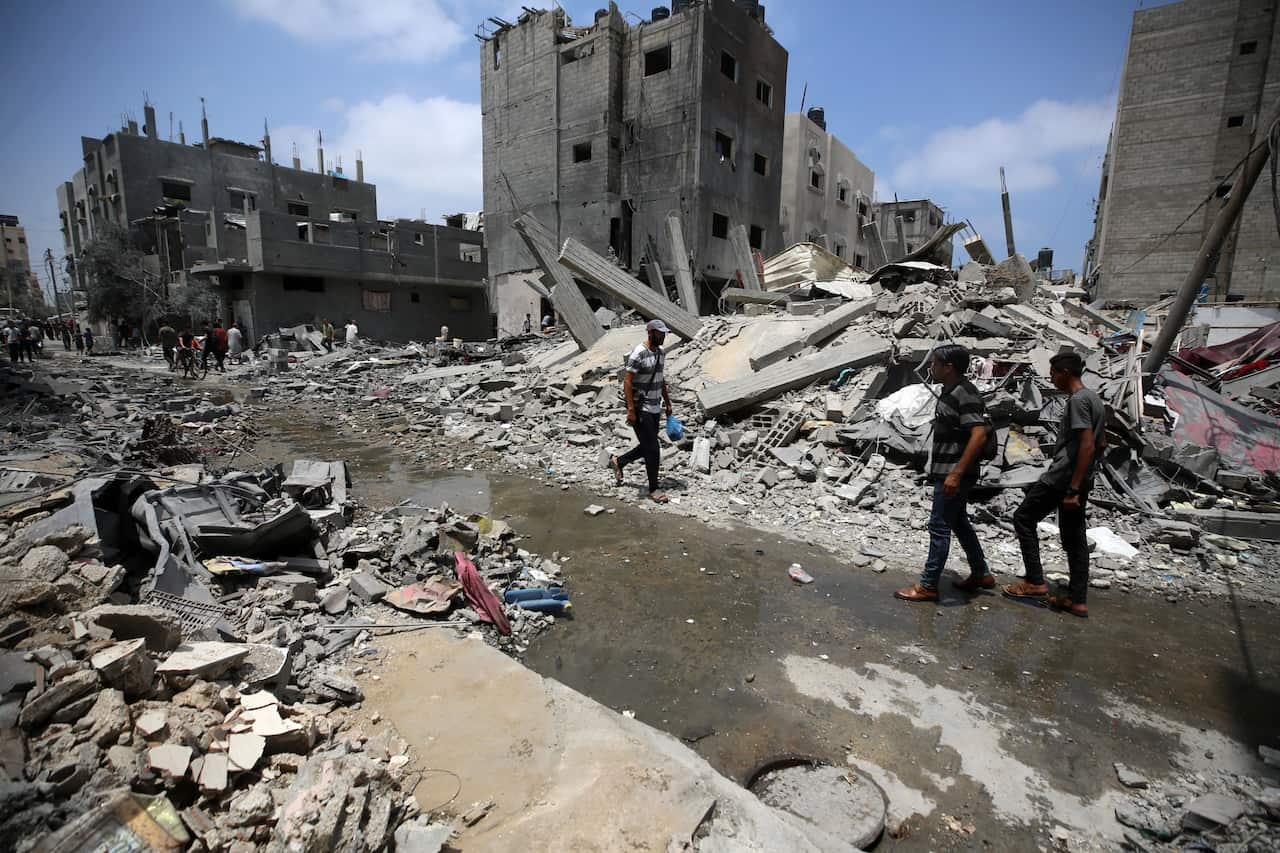 People standing in the rubble of destroyed buildings.