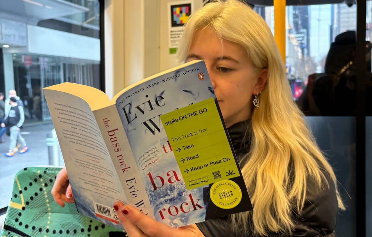 A blonde woman reading a book on a tram