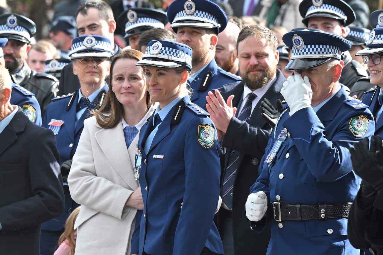 A female police officer surrounded by other officers.