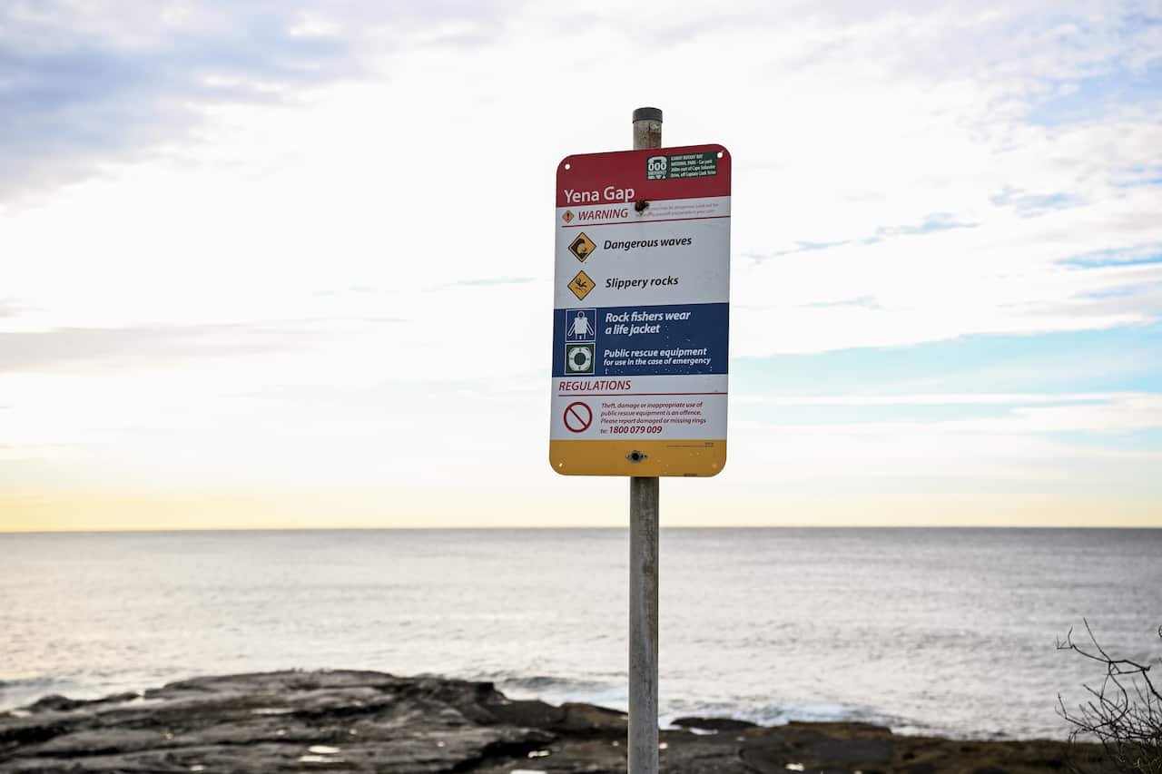 A white, red and yellow sign near the ocean.