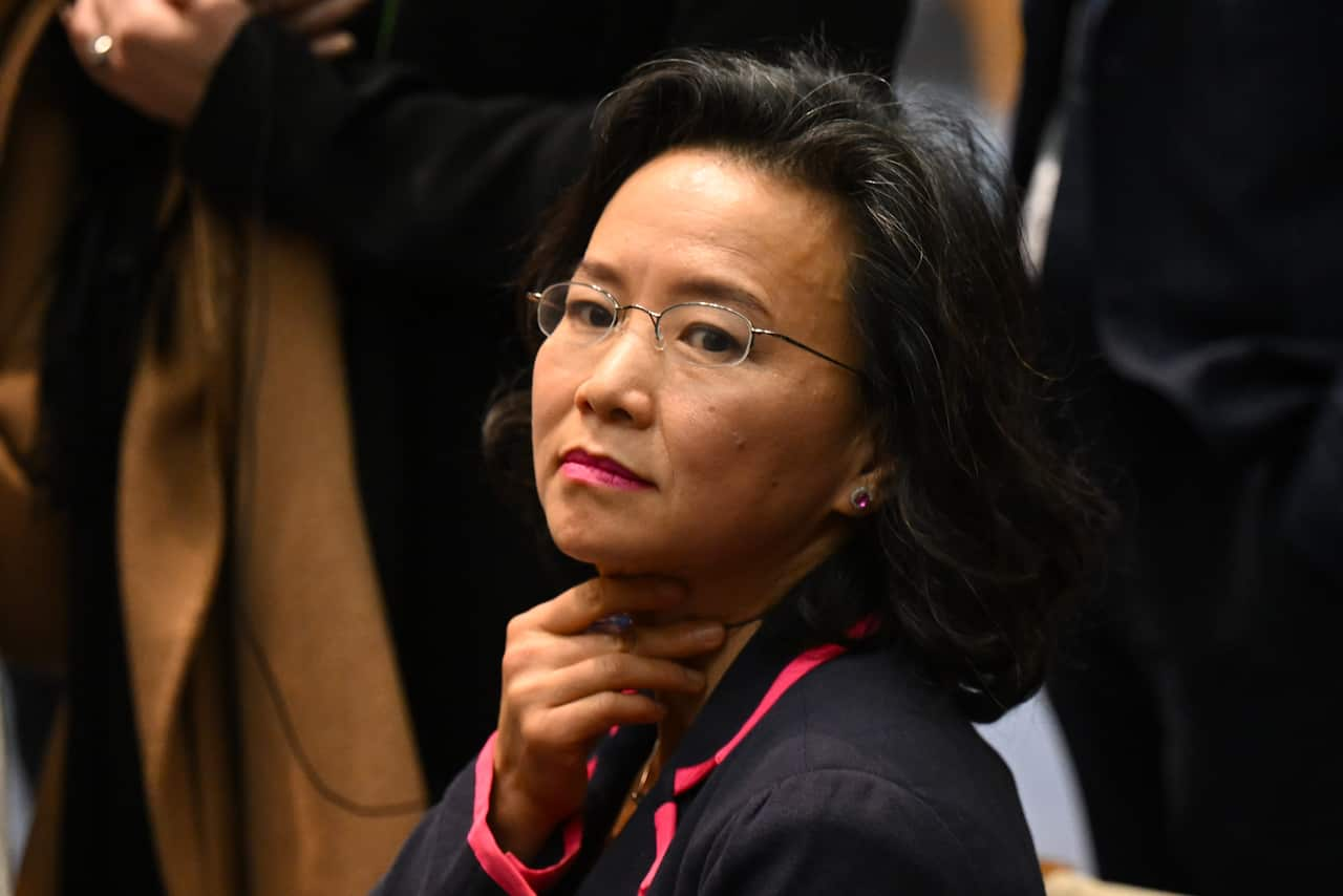 Cheng Lei in a crowd of people. She is holding her neck with her hand.