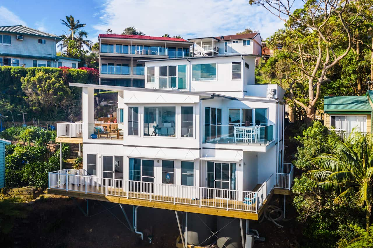 A three-storey home sits on a hill surrounded by other homes