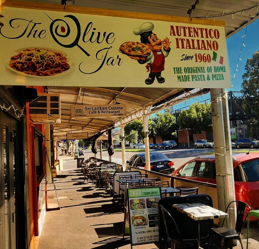 A restaurant with a sign and tables and chairs out the front