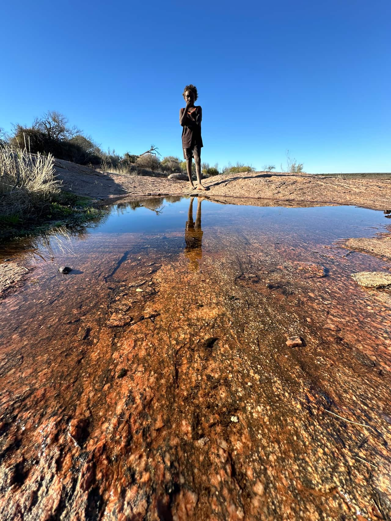 A child stands near a rock hole. 