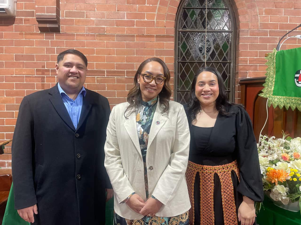 Two women and a man smile for a photo inside a church. 