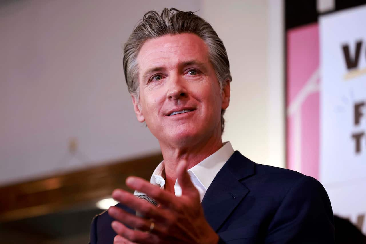 A man with short grey hair in a navy suit with a white shirt