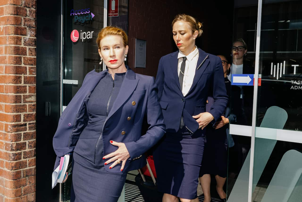 Two women in formal attire walking through a sliding glass door.