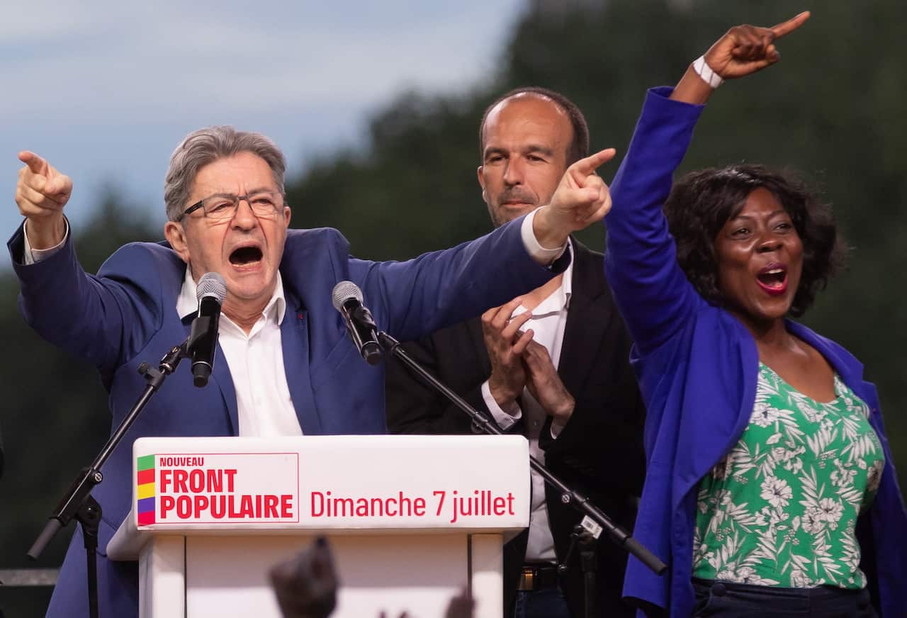 A man with his arms raised in the air in front of a podium, with a man and woman next to him.