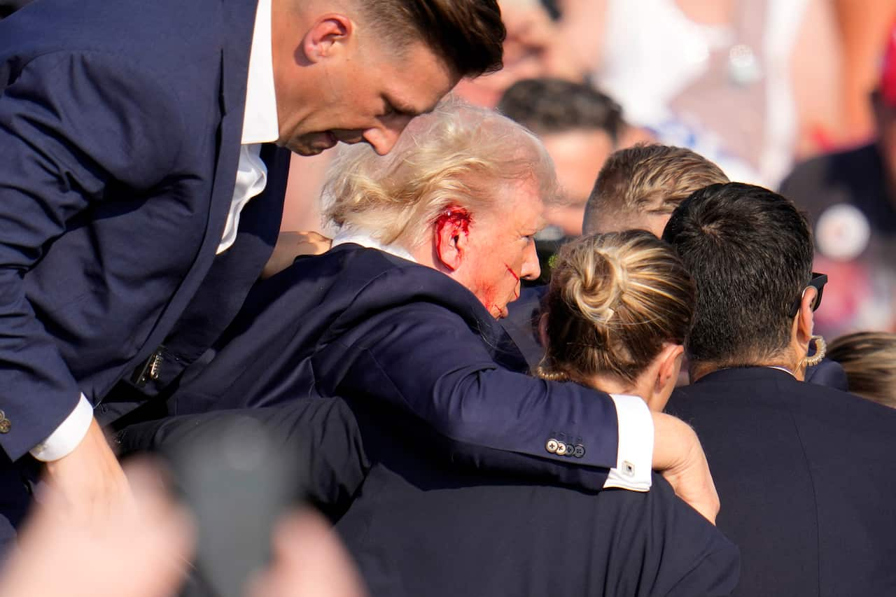 A man with a bleeding ear gets carried away by three others