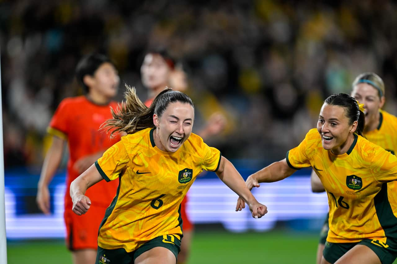 A woman in a yellow football shirt clebrating