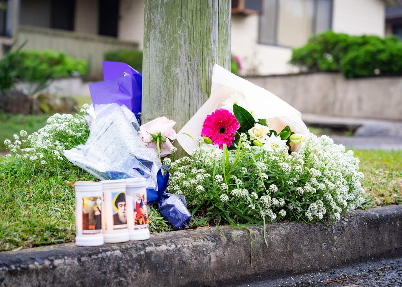 Flowers and candles on a sidewalk. 