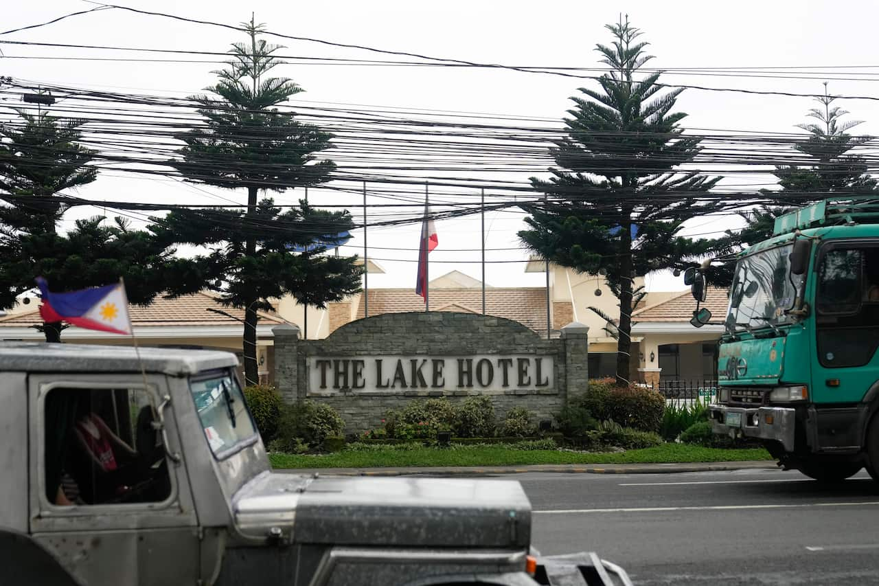 The entrance of The Lake Hotel, with two large vehicles drivings on the road in front 