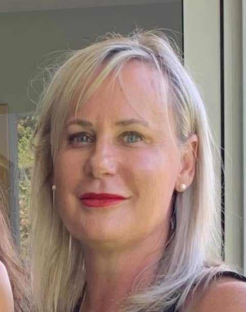 A woman with light blonde hair and red lipstick looking forward.