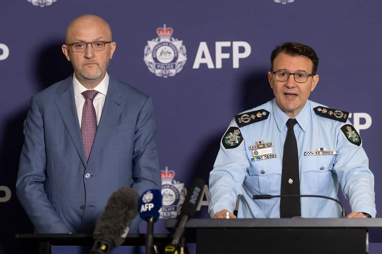 Australian Federal Police Commissioner Reece Kershaw speaking while standing at a lectern. Standing next to him is ASIO Director-General Mike Burgess.