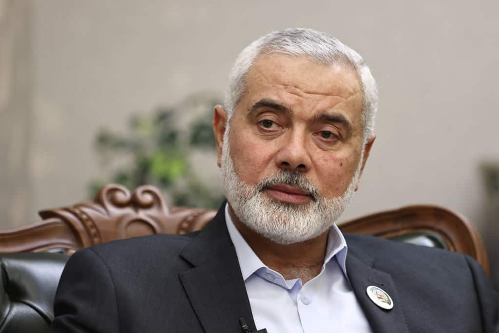 A man in a suit with a neatly trimmed grey beard looks at the camera with a neutral expression.