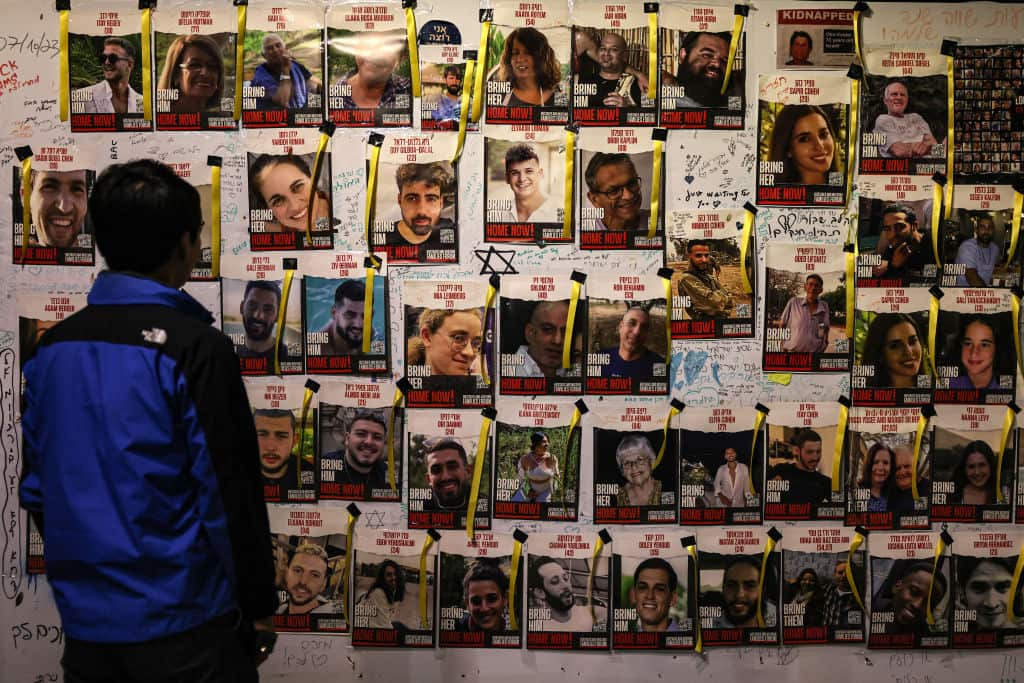 The rear of a person who looks at a wall of photos and names.