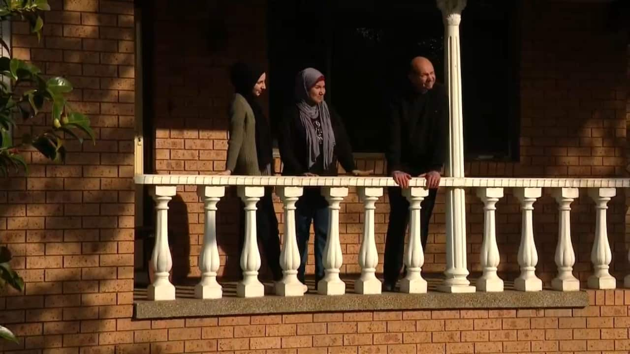 A group of people stand in front of a house