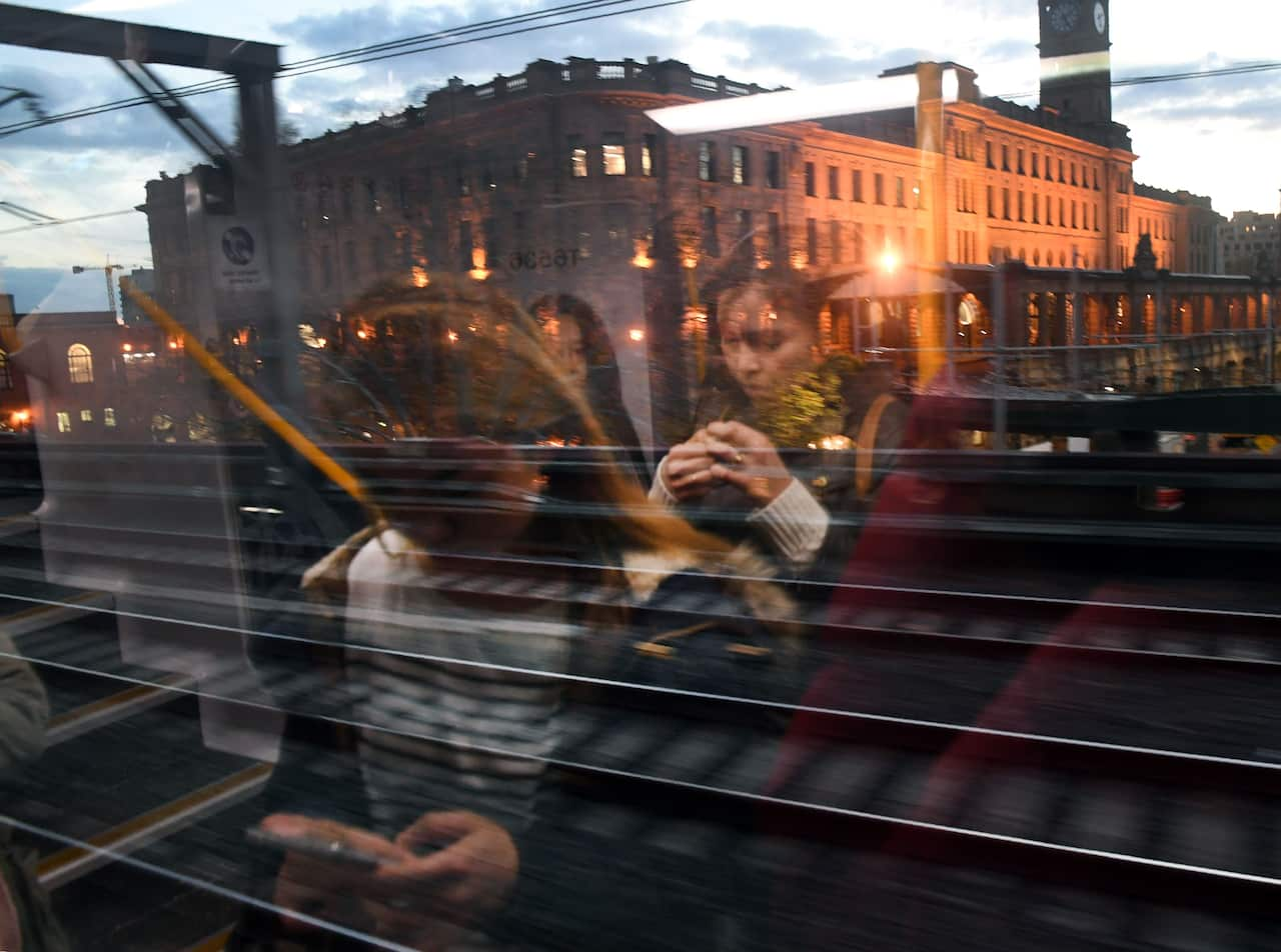 A composite image of people sitting on a train and a large building in the reflection.