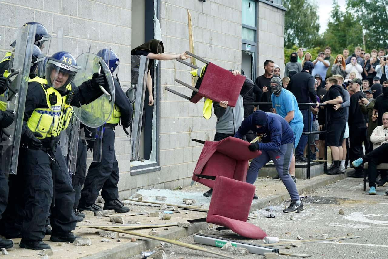 Masked men throw chairs at riot police outside a hotel 