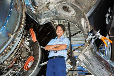 a woman standing in front of a plane engine