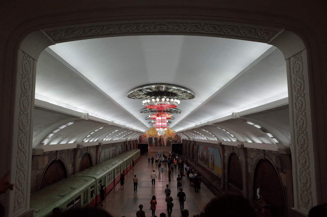 Passengers on Pyongyang's famous subway, which displays ornate coving and chandeliers.