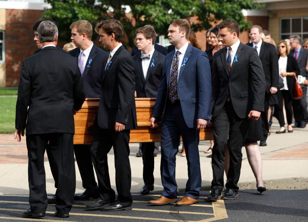 A group of men carry a wooden coffin.