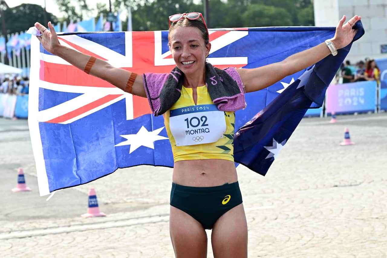 A female athlete in green and gold running attire poses with Australian flag.