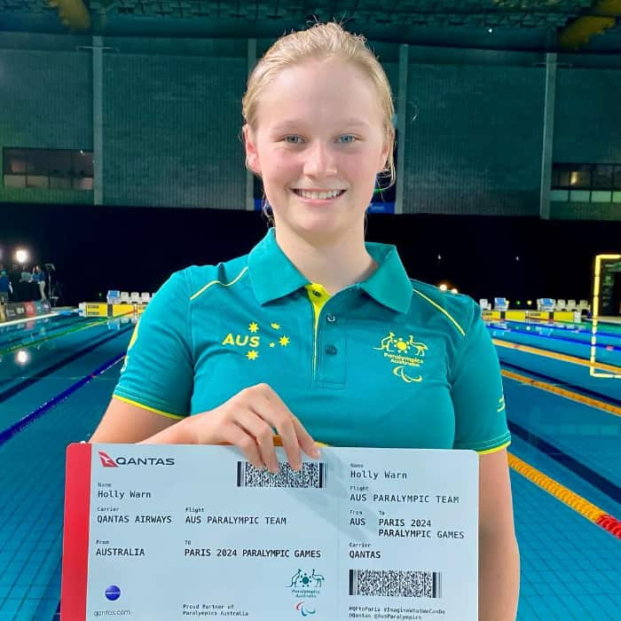 A girl standing in front of a pool holding a large boarding pass