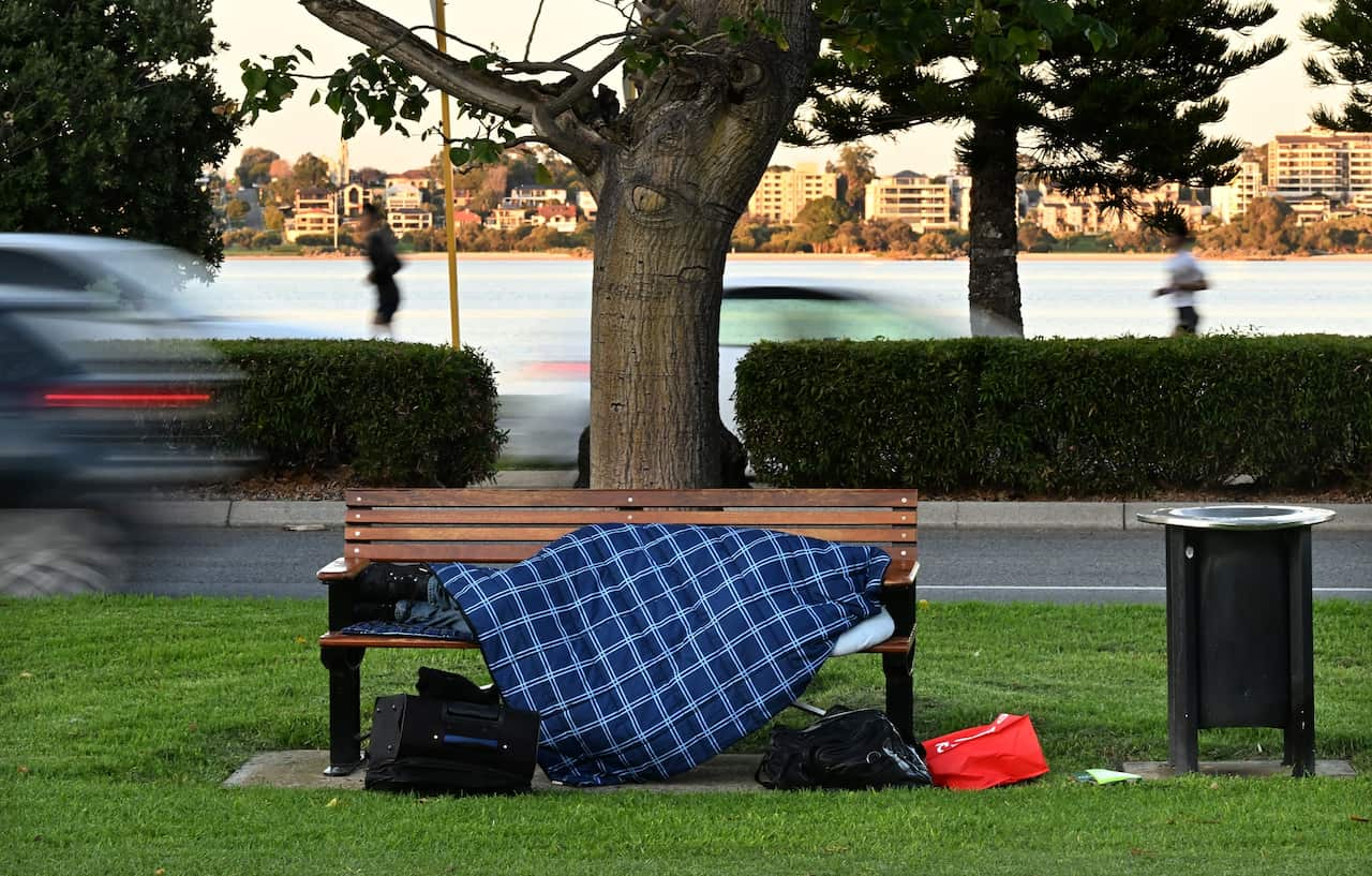 A homeless person is seen sleeping on a park bench in Perth. 