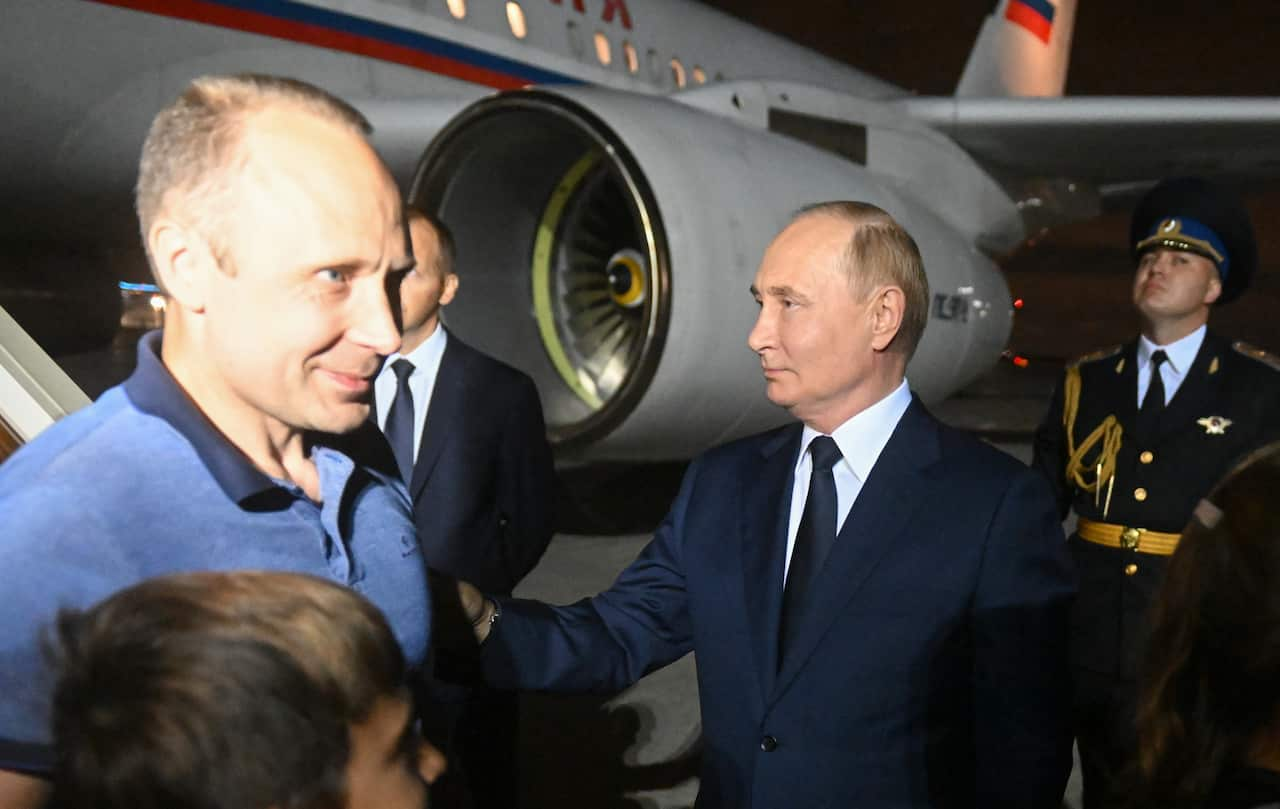 Vladimir Putin greeting a man next to an airplane. 