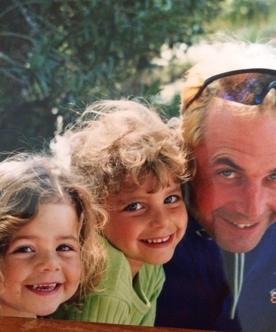 Two young children posing with their father 