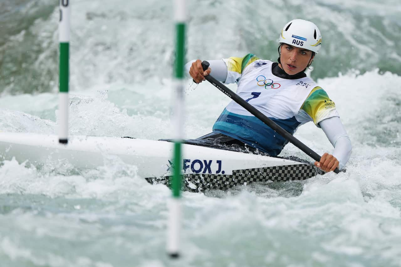 A woman paddles in a canoe through white water.