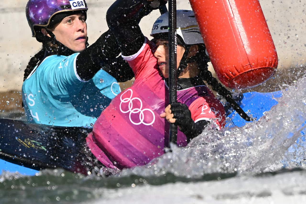 Two women in canoes pass close next to each other 