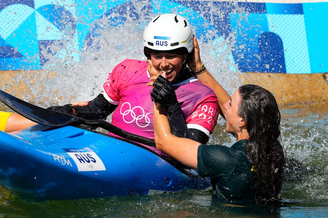 A woman in a kayak is hugged by another woman