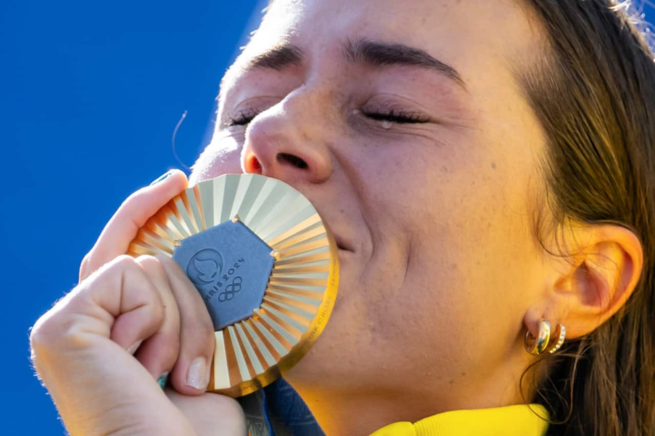 A woman sheds a tear as she kisses her gold medal.