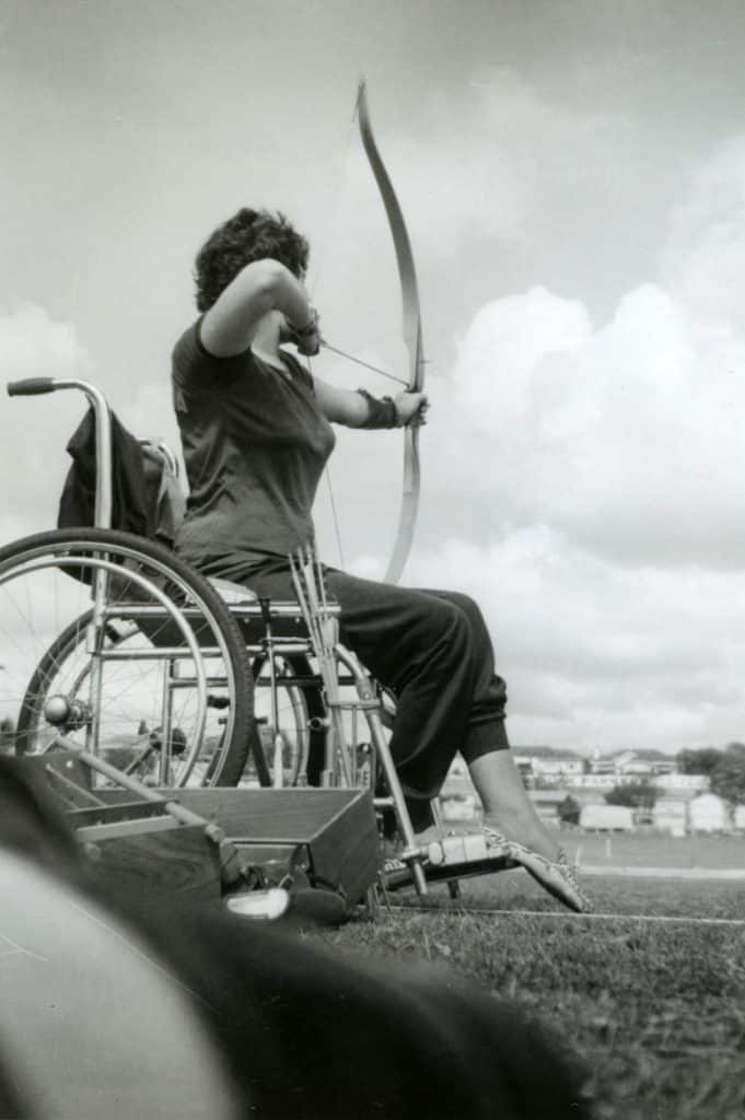 A woman in a wheelchair holds a bow and arrow