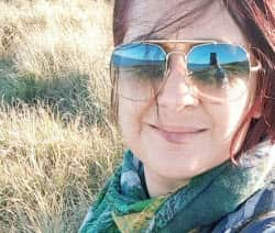 A selfie of a woman with dyed red hair, wearing aviator sunglasses