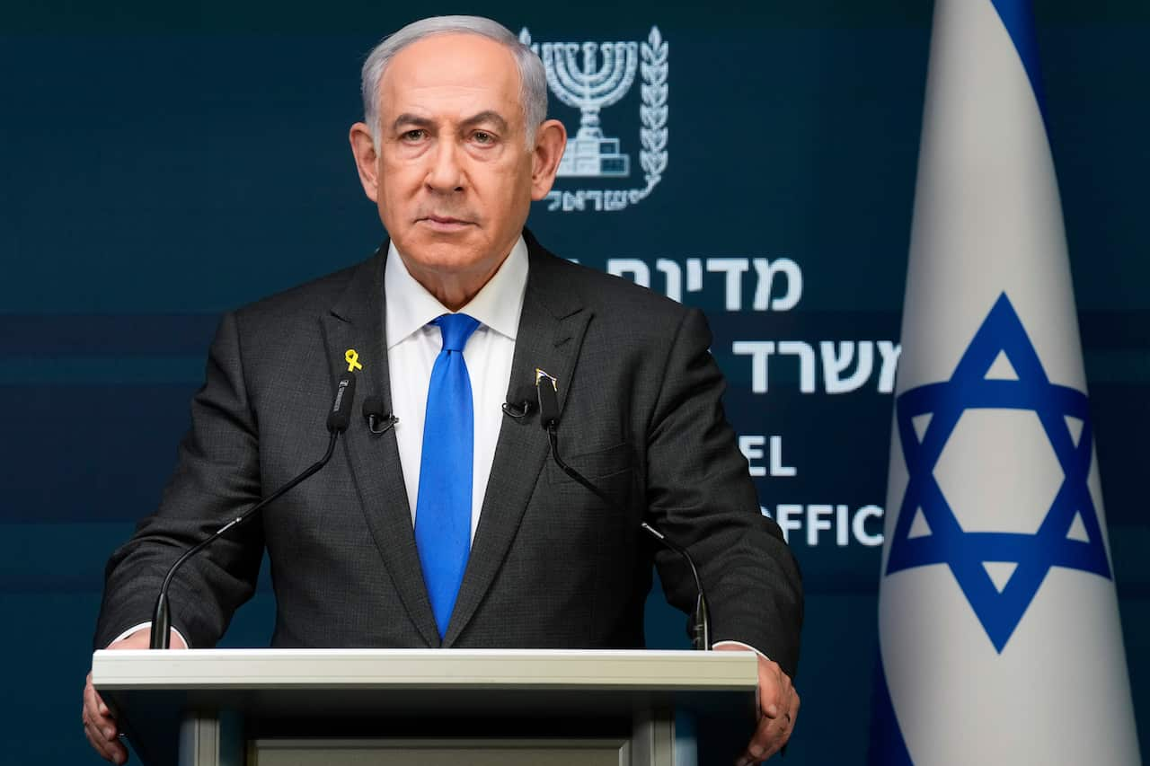 Benjamin Netanyahu standing at a podium. There is an Israeli flag behind him.