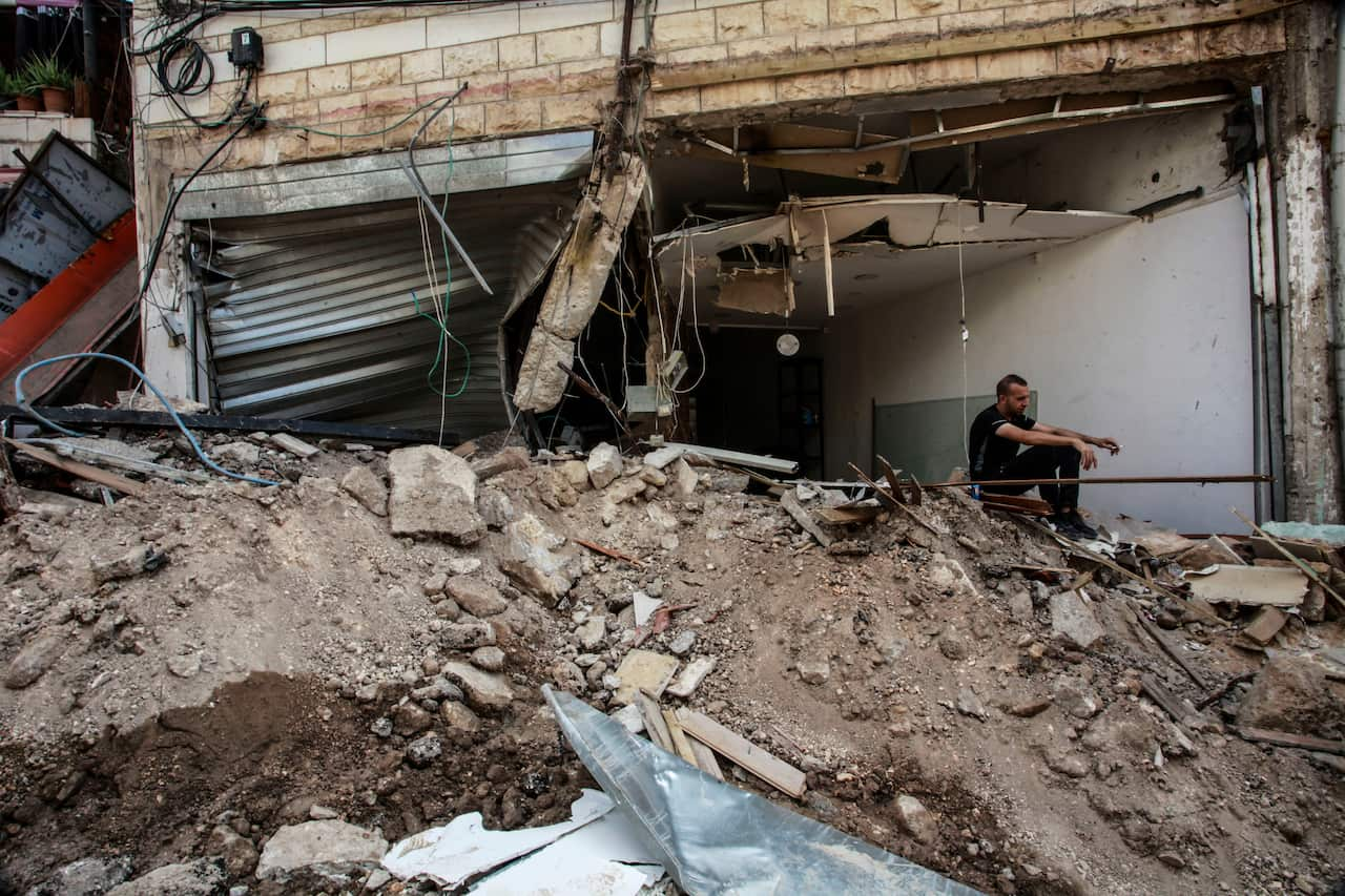 A man sitting in the rubble of a destroyed building.