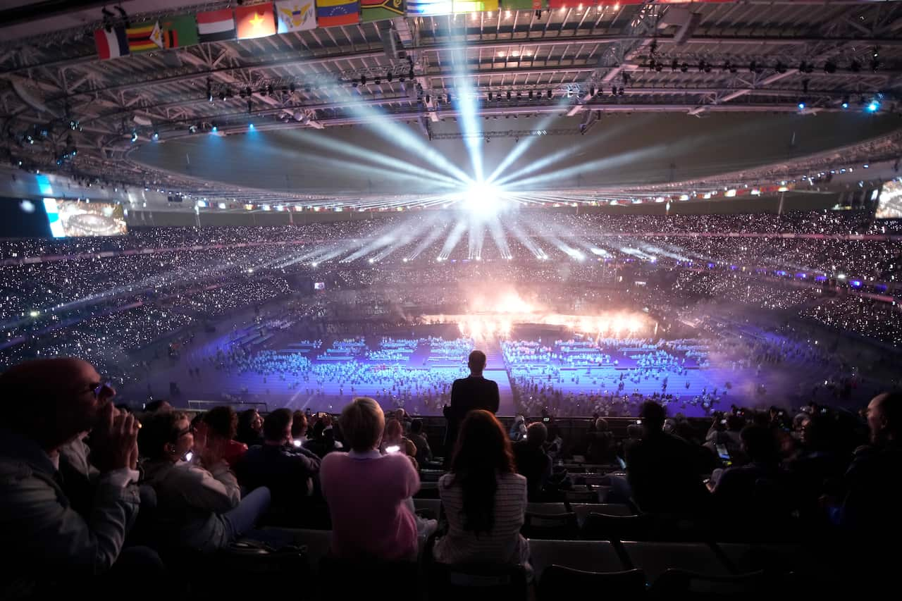 View of a stadium glowing blue while the audience watches.