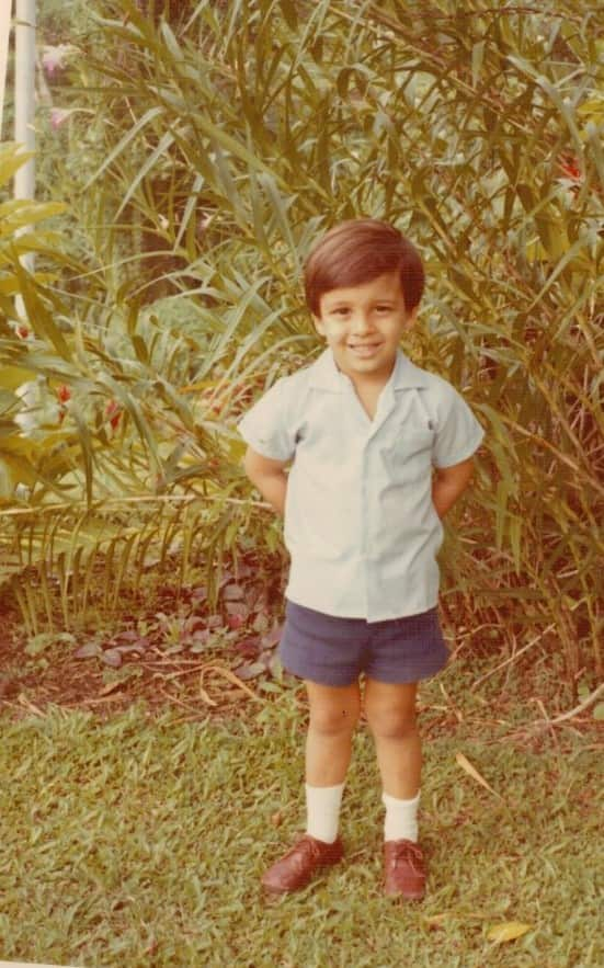 an old colour photo of a child standing in a backyard